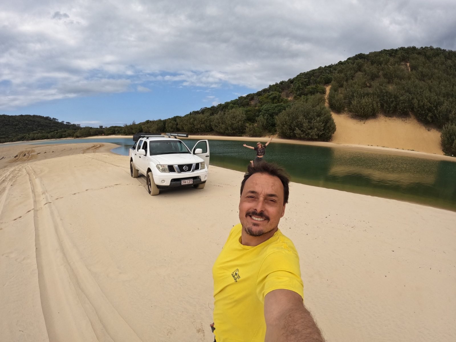 Marcelo numa praia da Austrália, com uma caminhonete 4x4 na areia